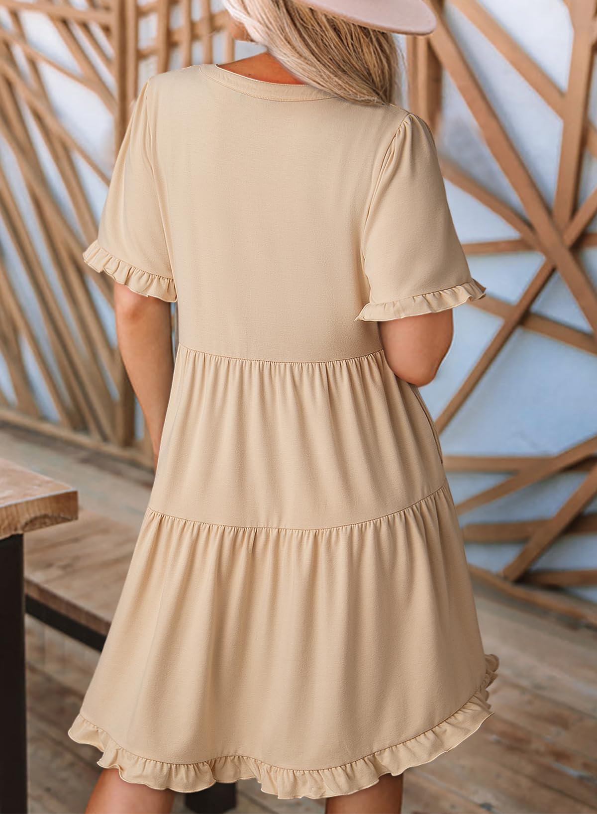 Beige dress with ruffled sleeves and hem worn by a person, against a wooden background.